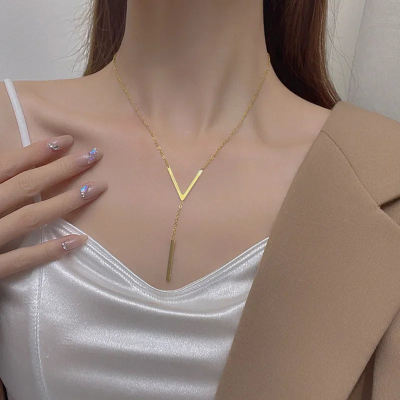 Gold necklace worn by a person with a neutral background